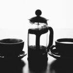 French press i filiżanki z kawą w czarno-białej tonacji