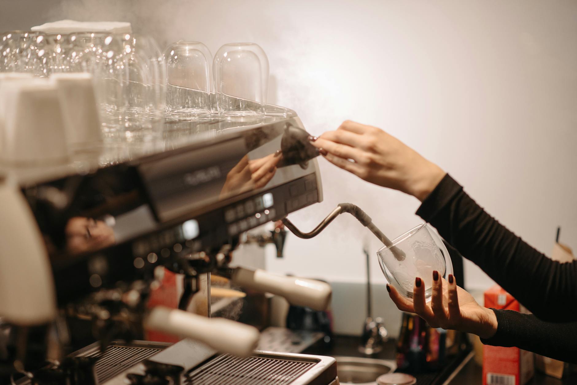 Barista spienia mleko dyszą ekspresu w kawiarni