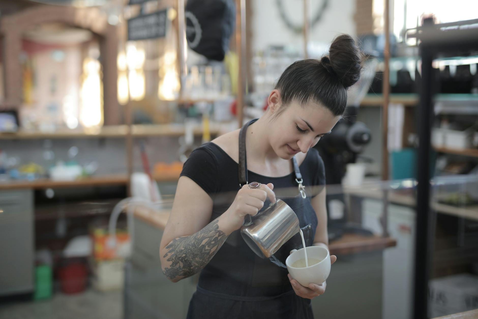 Barista w kawiarni wlewa mleko do cappuccino, tworząc delikatną piankę