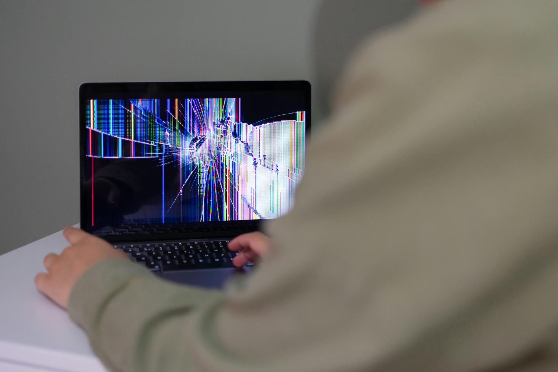 Osoba korzysta z laptopa z pękniętym, zniekształconym ekranem