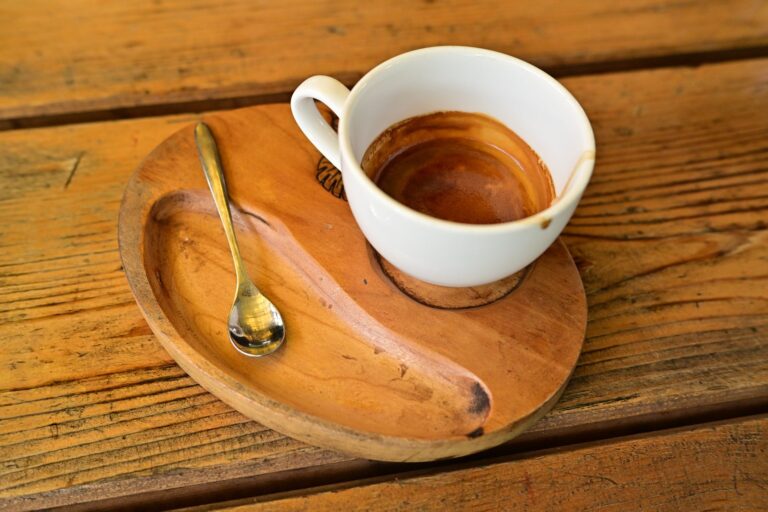 Pusta filiżanka po espresso na drewnianym spodku z łyżeczką